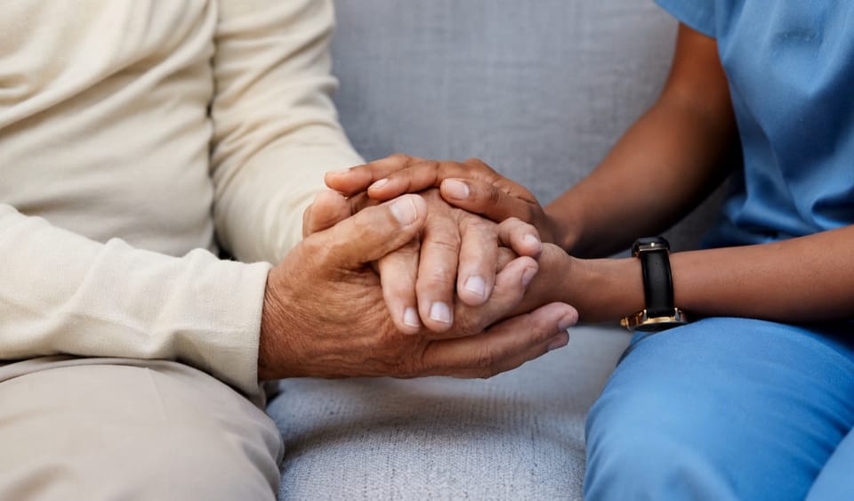 Caregiver holding an older person's hands in a care setting